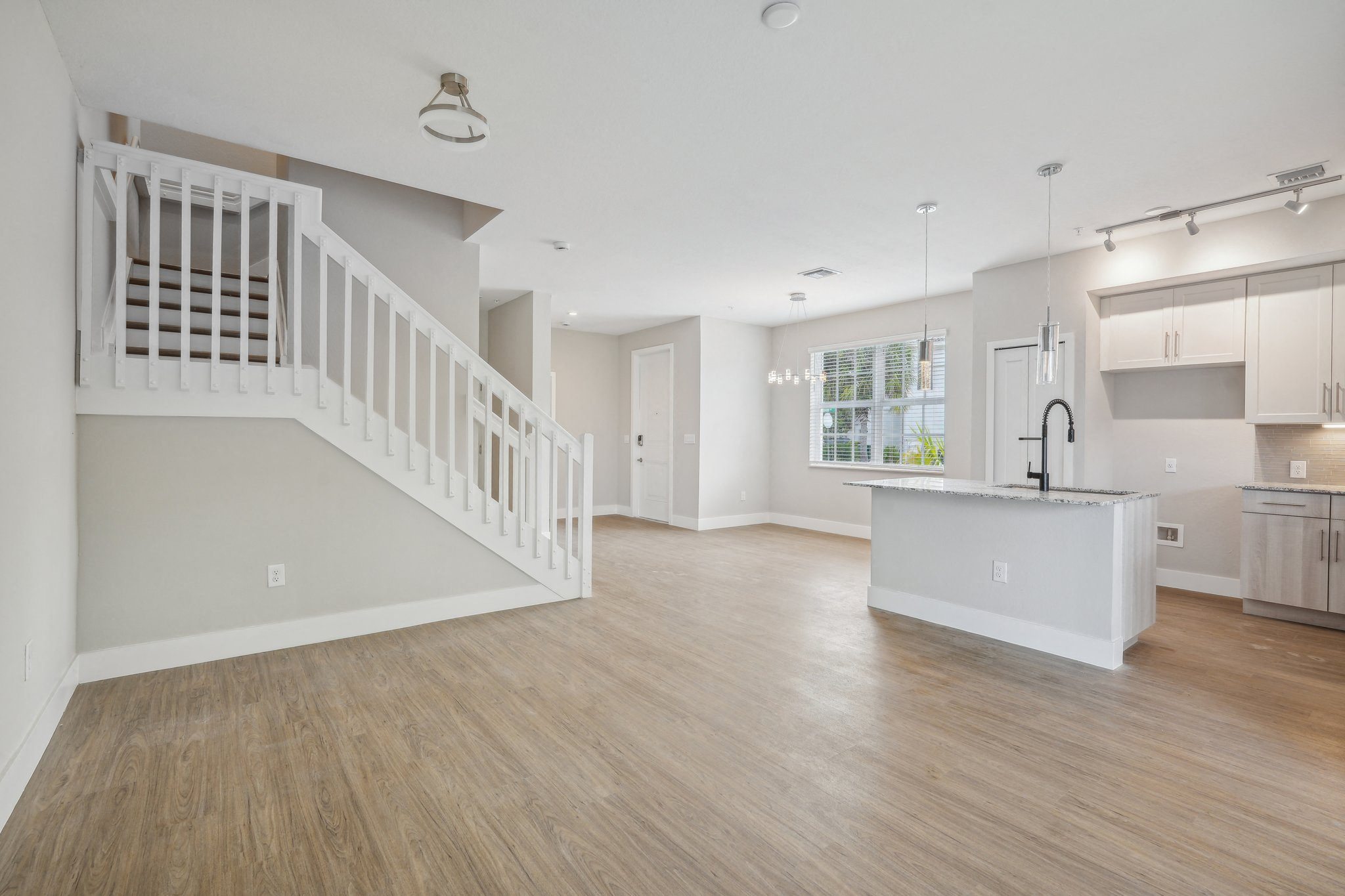 an open kitchen and living room with a white staircase